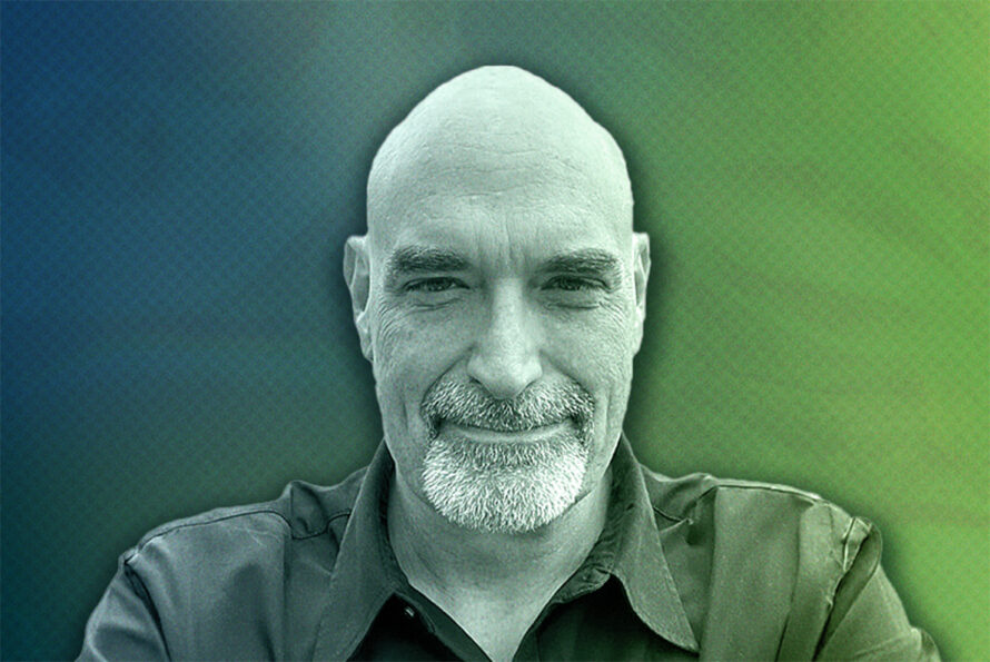 Portrait of a smiling researcher, wearing a collared shirt, on a blue and green gradient background.